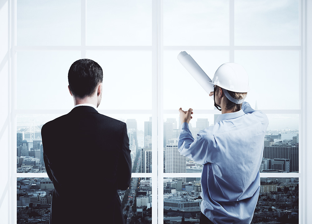 Back view of worker explaining something to businessman through window with city view. Architecture concept